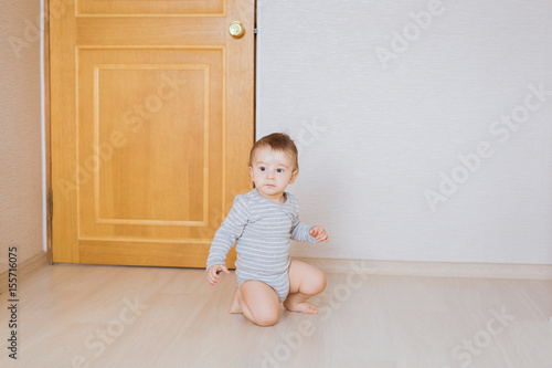 Cute baby boy toddler sitting on the floor in bedroom