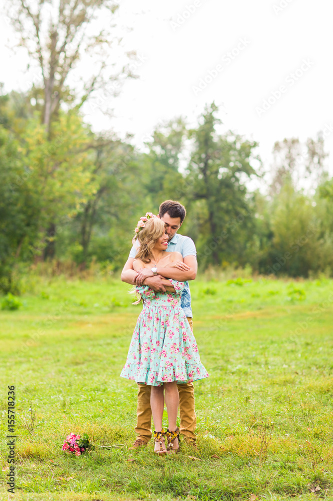 Couple embracing on nature. Young romantic man and woman standing and hugging each other with tenderness outdoors. Young love concept.
