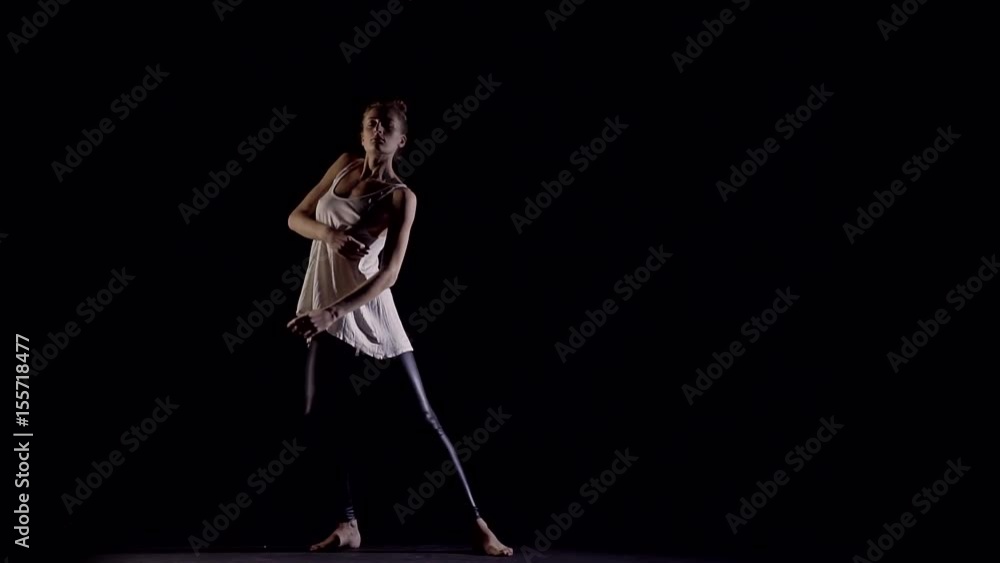 Seductive movement in tall, slender girl in a dark room illuminated the silhouette Seductive movement in tall, slender girl in a dark room illuminated the silhouette
