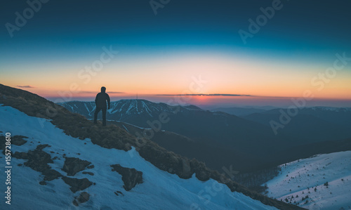 Hiker stands on a hill and look to the horizon. Instagram stylization
