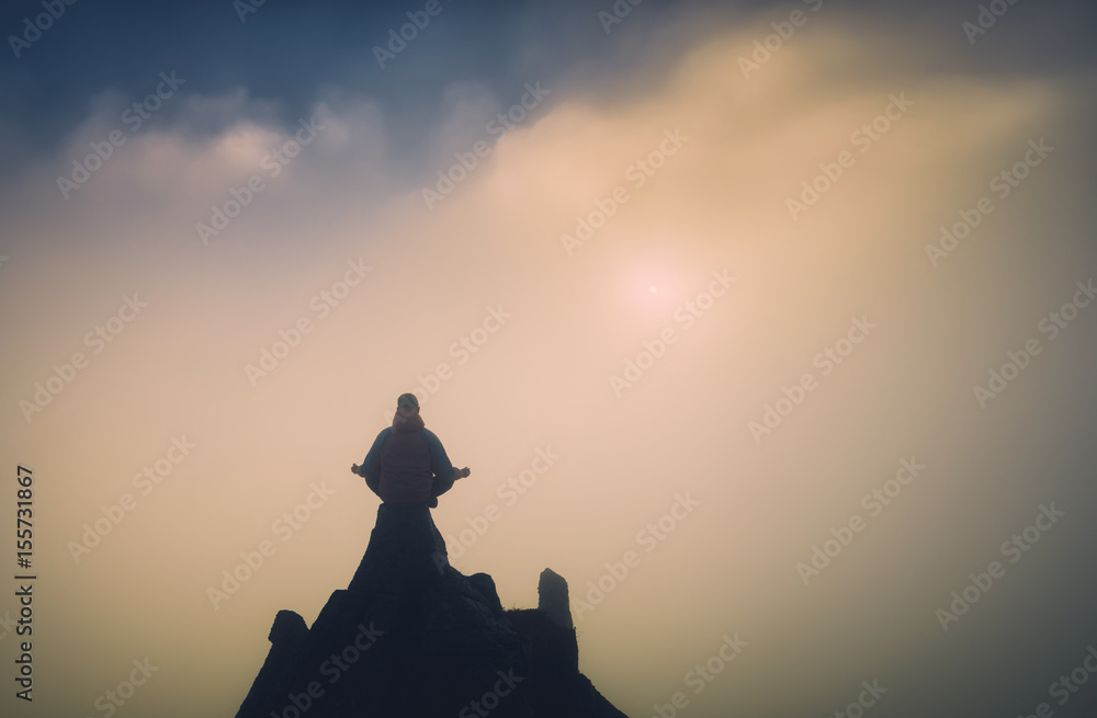 Human meditating on the top of a mountain. Instagram stylization