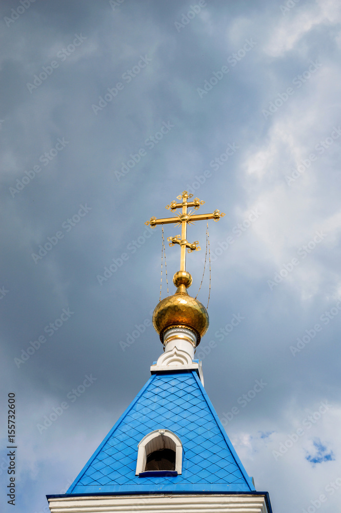 Orthodox cross at church rooftop against blue sky
