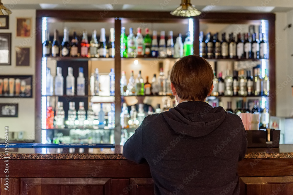 Back view young man sits at modern bar counter Back view young man sits at modern bar counter