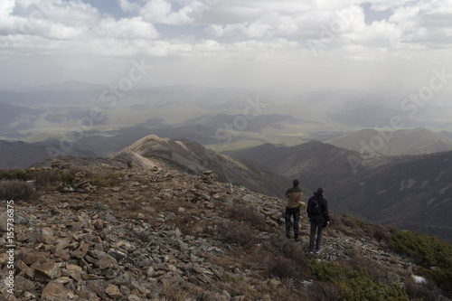 Two people stand side by side on top of the mountain and admire the mountain scenery © evgenzz