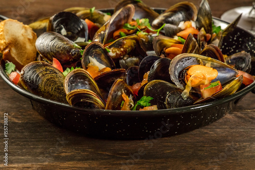 Skillet of marinara mussels on rustic background
