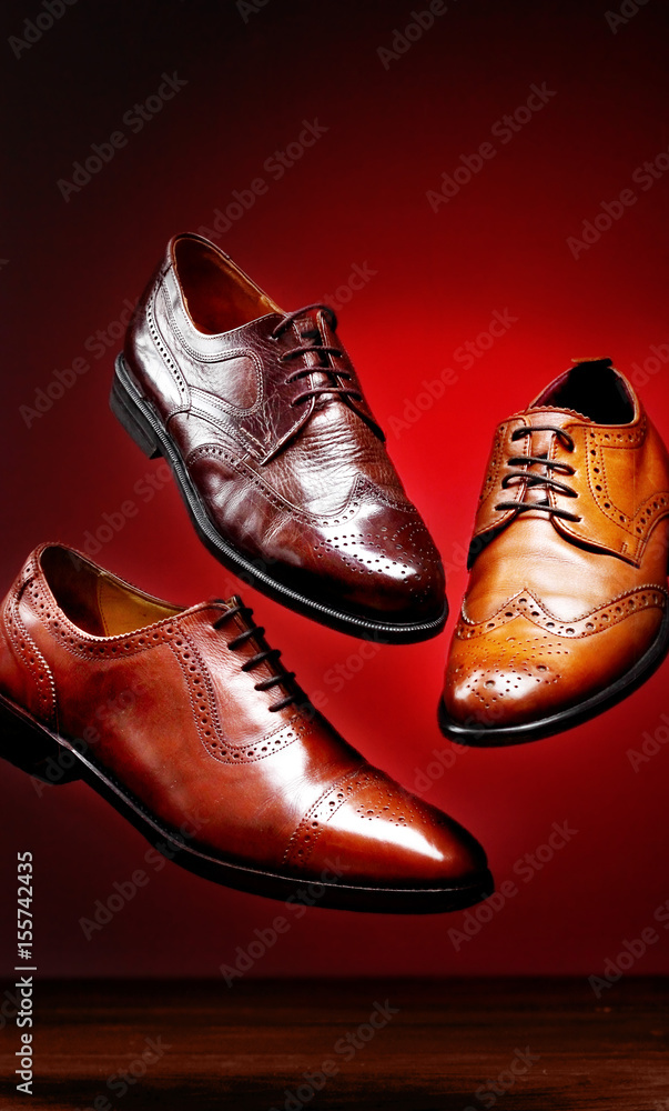Fashion classical polished men's brown oxford brogues shades of brown oxford brogues.Conept flying shoes.Closeup.Red background