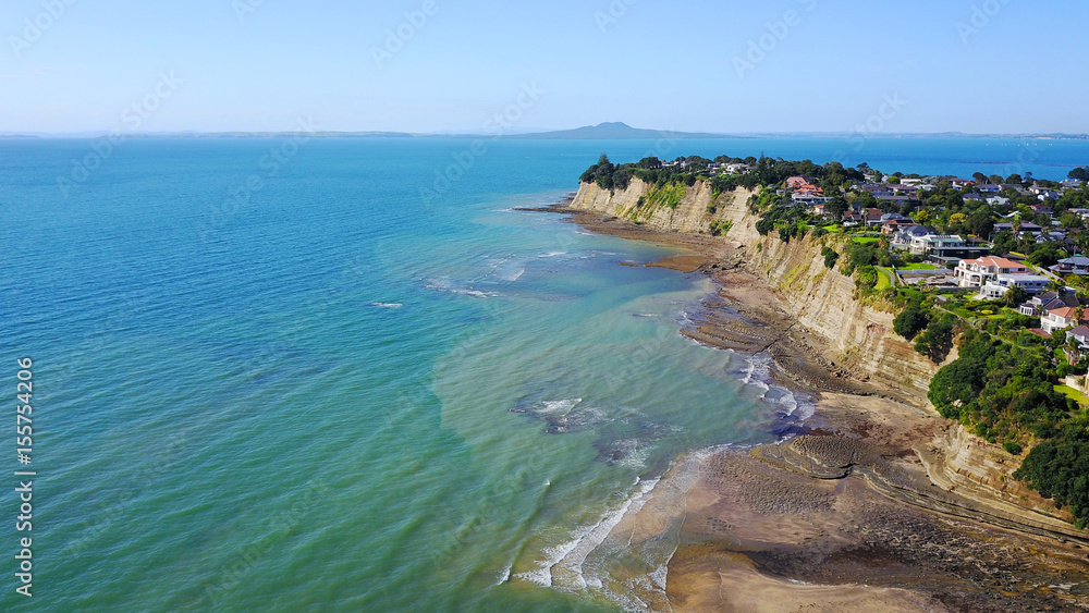 Aerial view on sunny beach with residential suburb on the background. Auckland, New Zealand.