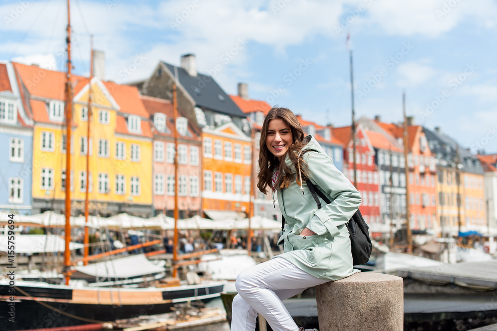 Happy young tourist woman with backpack at Copenhagen, Nyhavn, Denmark. Visiting Scandinavia, famous European destination during fall or spring. Travel and Lifestyle. Happy young tourist woman with backpack at Copenhagen, Nyhavn, Denmark. Visiting Scandinavia, famous European destination during fall or spring. Travel and Lifestyle.