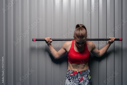 Fitness woman posing with barbell on shoulders