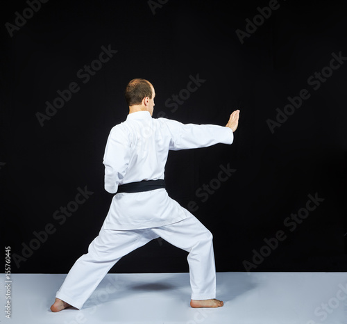 On a white surface, an adult athlete trains a block with his hand