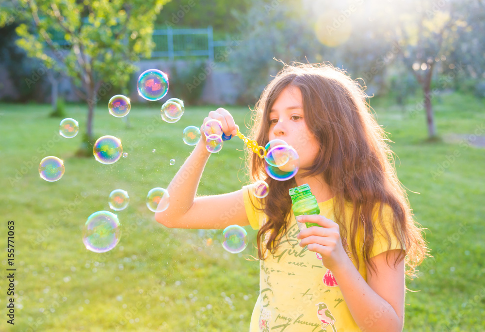 Girl blowing soap bubbles outdoors