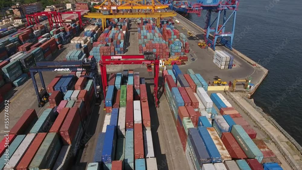 Commercial port zone of Vladivostok Russia  Primorsky Krai local industrial shipping containers cranes transport. Golden bridge unloading Freight city panorama. Summer. Aerial flight forward