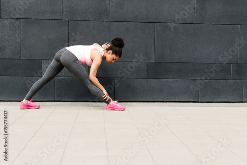 Fototapeta Naklejka Na Ścianę i Meble -  Young female runner warming up her body before training