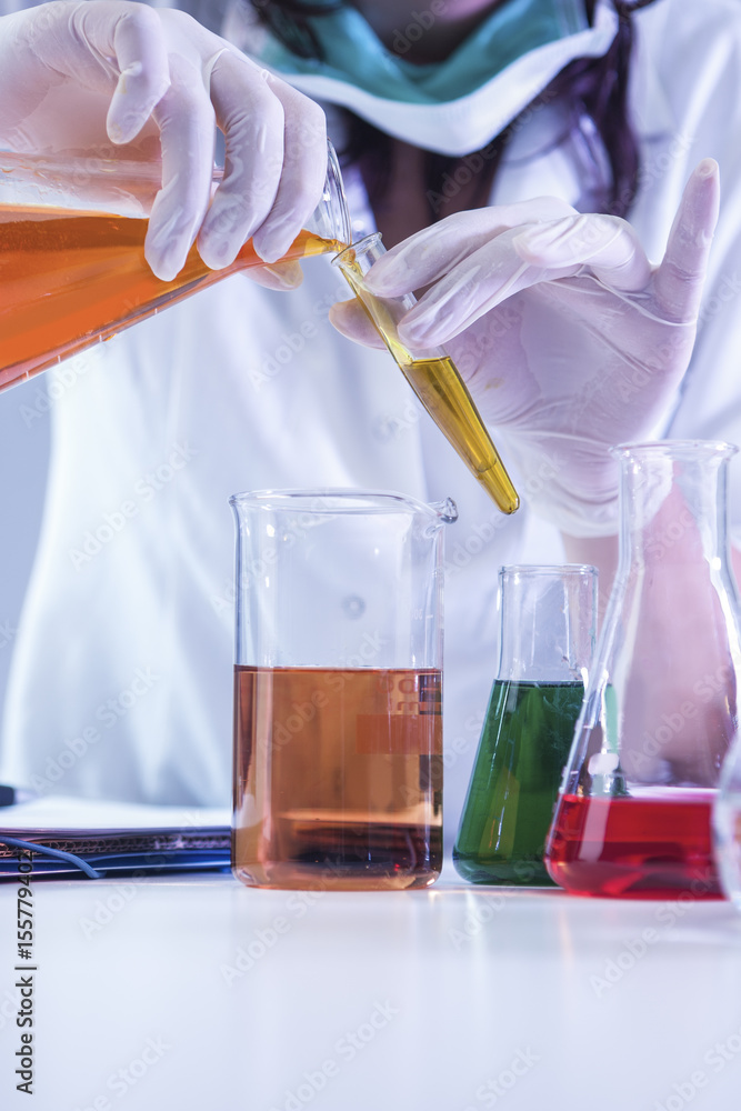Closeup of hands of Female Laboratory Worker Dealing With Flasks Containing Liquid Chemicals. Closeup of hands of Female Laboratory Worker Dealing With Flasks Containing Liquid Chemicals.