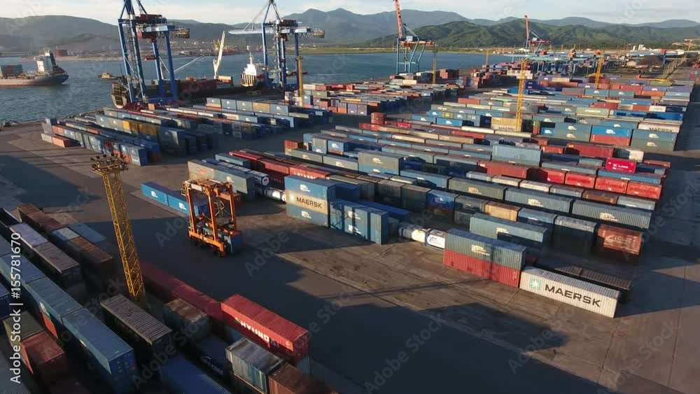 Unique drone flight above Vostochny Port intermodal container terminal. Bridge cranes Handling large tonnage ship. Special industry cars. Nakhodka and Vladivostok, Russia. Japan sea. Summer sunset. Unique drone flight above Vostochny Port intermodal container terminal. Bridge cranes Handling large tonnage ship. Special industry cars. Nakhodka and Vladivostok, Russia. Japan sea. Summer sunset.