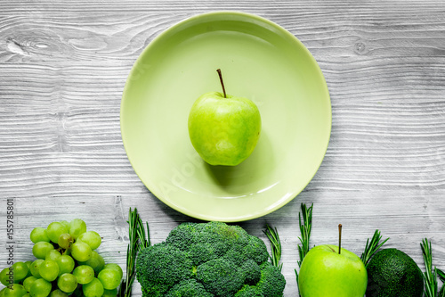 green fresh vegetables, fruits and apple on plate for healthy salad ligth background top view photo