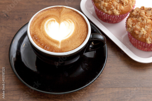 Obraz na płótnie Coffee cup of latte art heart shape beside with muffins on wooden background w salonie