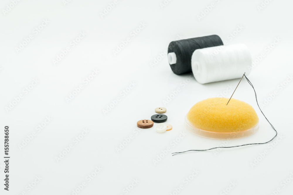 Black and white sewing threads, needle and buttons isolated on white background