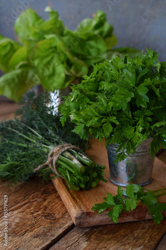 Composition of green herbs and vegetables. Organic spring mix for salad on brown wooden background. Lettuce, parsley, dill, chard.