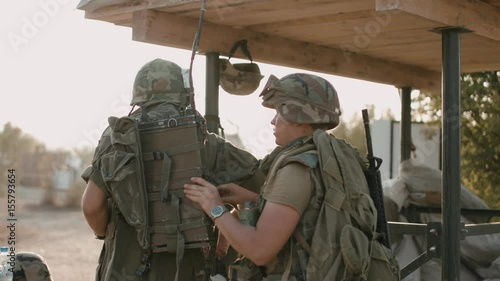 American soldier helps another to pack equipment on the military campaign