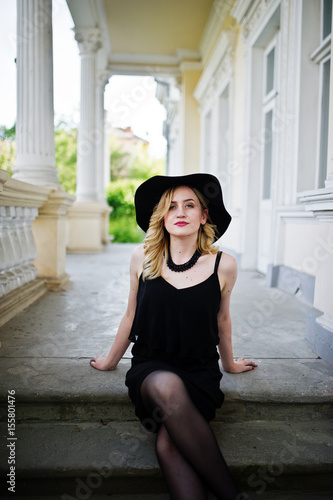 Blonde woman on black dress, necklaces and hat against vintage house. Free Download Blonde woman on black dress, necklaces and hat against vintage house. - GFXLoad