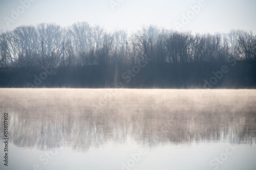 A misty dawn on the river in the early morning in the village © mironovm