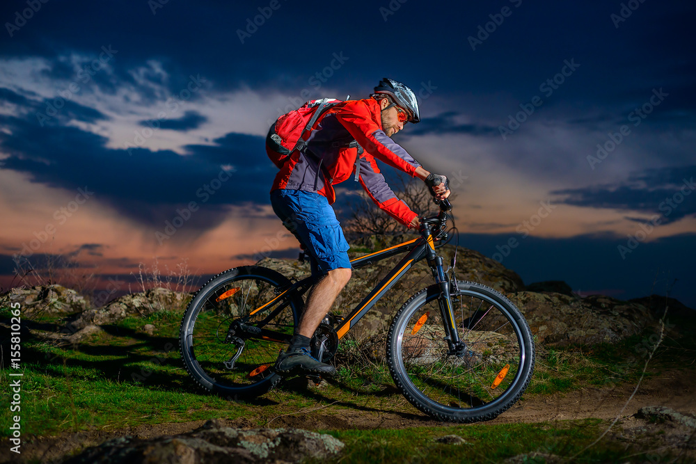 Fototapeta premium Cyclist Riding Mountain Bike on Spring Rocky Trail at Beautiful Sunset. Extreme Sports and Adventure Concept.