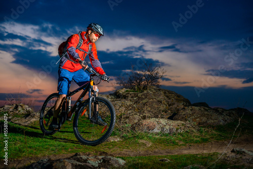 Cyclist Riding Mountain Bike on Spring Rocky Trail at Beautiful Sunset. Extreme Sports and Adventure Concept.