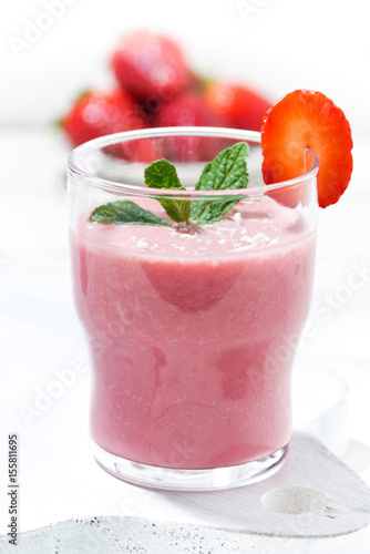 refreshing strawberry milkshake on white table, vertical closeup