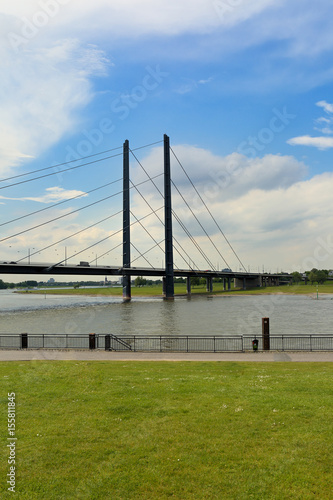 Long metal bridge above the Rhine river in Dusseldorf, Germany in sunny summer day under blue sky. Vertical composition