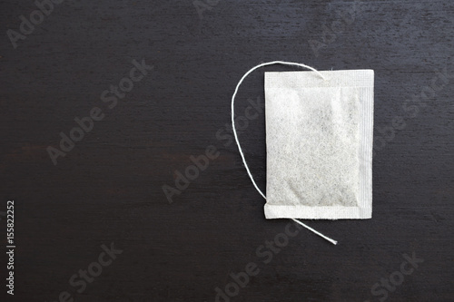 White tea bag on black wood background © sirirak