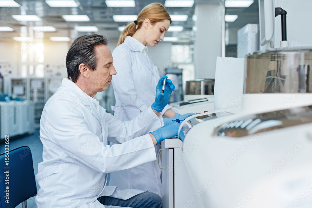 Serious technician doing blood analysis Serious technician doing blood analysis