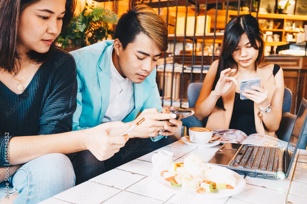 Fototapeta premium Group of three young business people gathered together with laptop at a table discussing