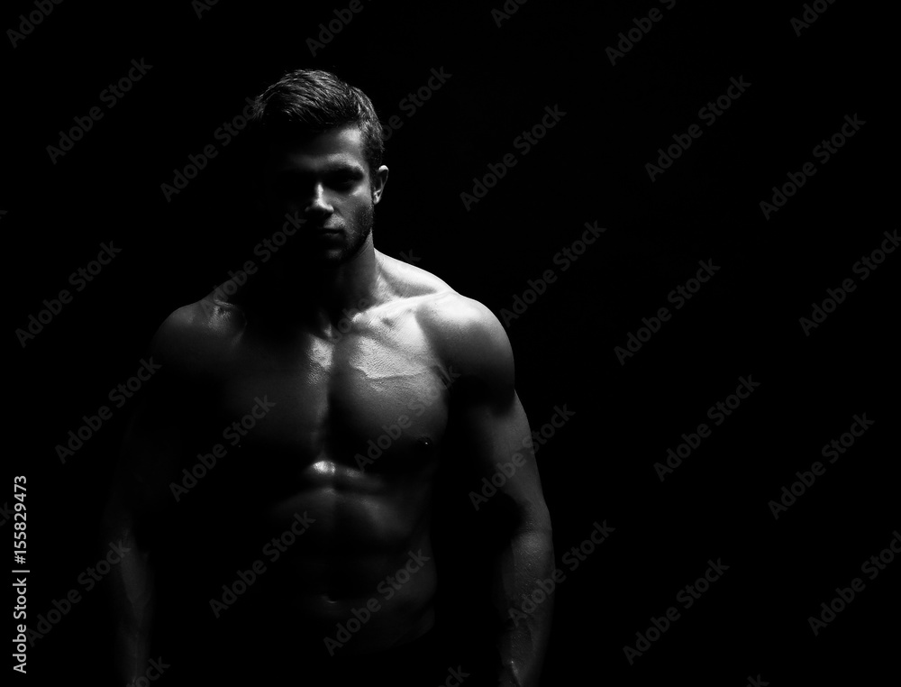 Obraz premium Black and white studio shot of a strong unrecognizable young handsome male athlete posing shirtless on black background copyspace bodybuilder man with muscular body fitness sports willpower concept.
