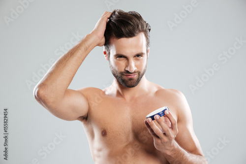 Man straighten hair and holding cream isolated