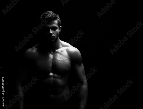 Black and white studio shot of a strong unrecognizable young handsome male athlete posing shirtless on black background copyspace bodybuilder man with muscular body fitness sports willpower concept.