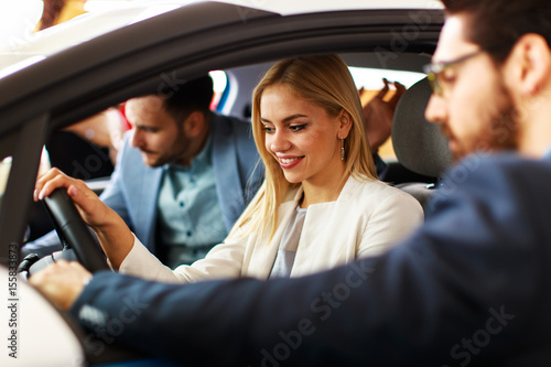 Young couple choosing new car for buying in dealership shop © djile