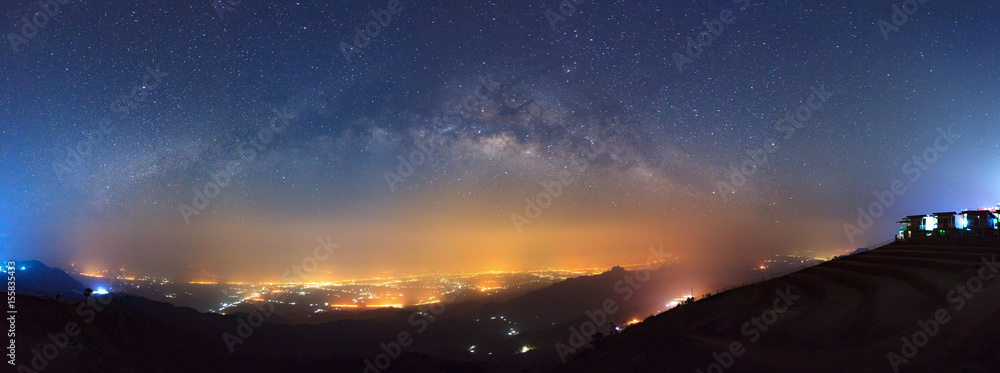 Obraz premium Panorama Milky way galaxy and city light at Phutabberk Phetchabun in Thailand.Long exposure photograph.With grain