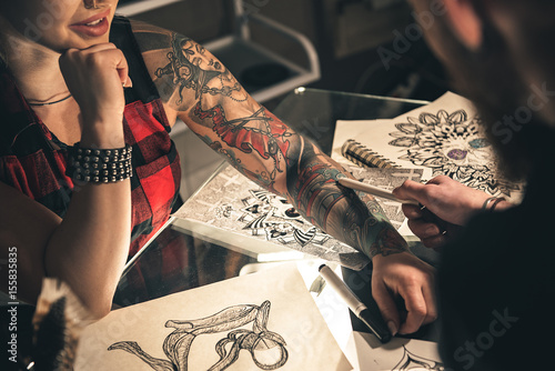 Female hand with tattoo situating on desk photo