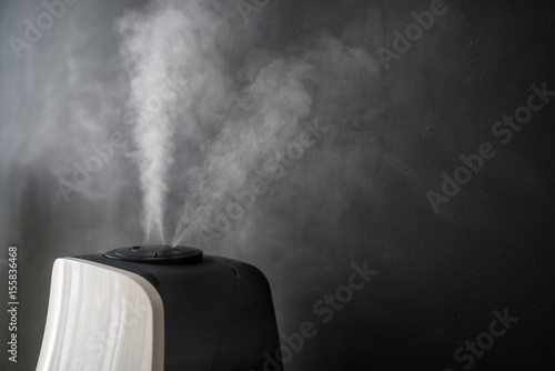 Foto humidifier distributes steam in the living room against the background of a black chalkboard