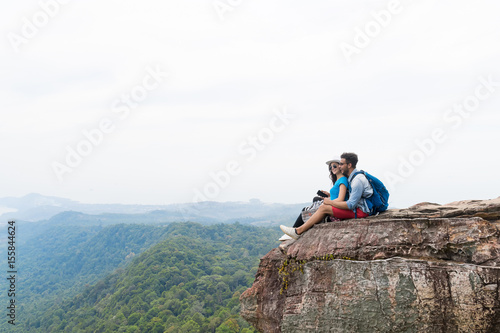 Couple With Backpacks Sit Embracing On Mountain Top Enjoy Landscape, Young Man And Woman Tourist Backpackers On Hike