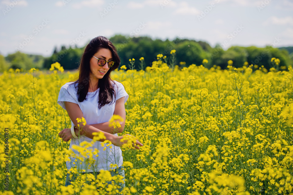 Lovely brunette in sunglasses stay in rapeseed field. Spring. Lovely brunette in sunglasses stay in rapeseed field. Spring.