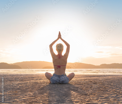 Young Girl Sitting Lotus Pose On Beach At Sunset, Beautiful Woman Practicing Yoga Summer Vacation Meditation Seaside Sea Ocean Holiday Travel