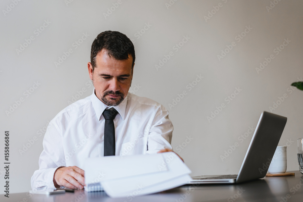Attentive businessman reading an important document at office Attentive businessman reading an important document at office