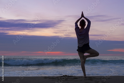 Girl on the beach doing yoga by the sea