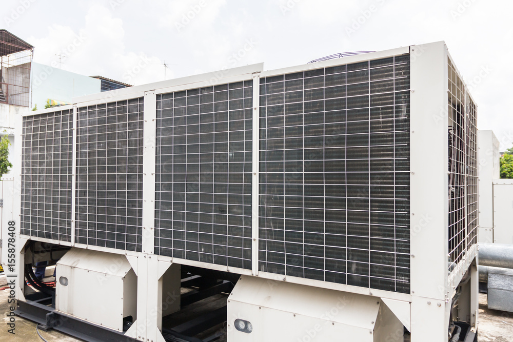 The technician is repairing the electrical system. Industrial air conditioning units. A plurality of cooling units installed in the wall of a building. The technician is repairing the electrical system. Industrial air conditioning units. A plurality of cooling units installed in the wall of a building.