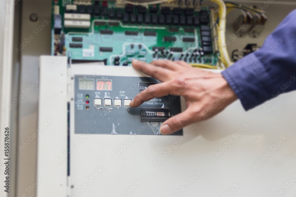 The technician is repairing the electrical system. Industrial air conditioning units. A plurality of cooling units installed in the wall of a building. The technician is repairing the electrical system. Industrial air conditioning units. A plurality of cooling units installed in the wall of a building.