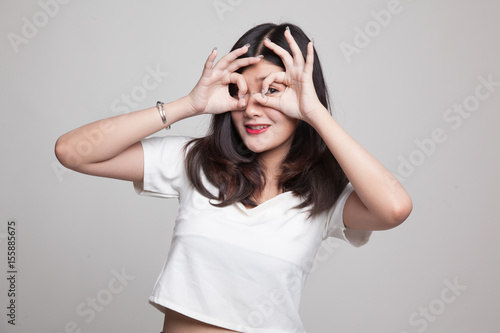 Asian woman do funny double OK sign as glasses.