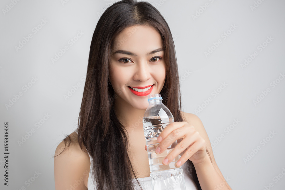 Young beautiful Asian woman with smiley face and red lips holding a water bottle. Young beautiful Asian woman with smiley face and red lips holding a water bottle.