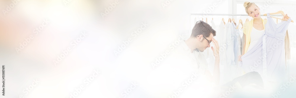 Bored man with shopping bags while woman at clothes rack Bored man with shopping bags while woman at clothes rack